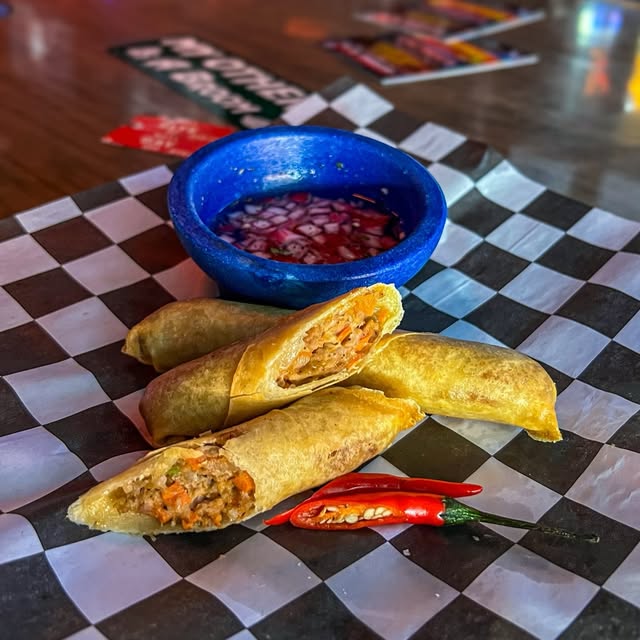 Crispy lumpia with a chili dipping sauce on checkerboard paper