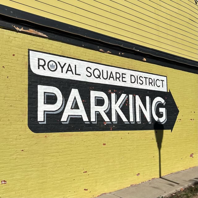 Painted Royal Square District parking mural on a yellow brick wall